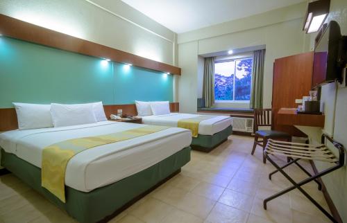 A bed or beds in a room at Microtel by Wyndham Tarlac