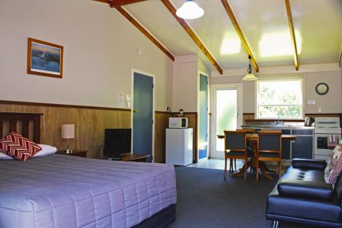 a bedroom with a bed and a living room and a kitchen at Fairy Springs Motel in Rotorua