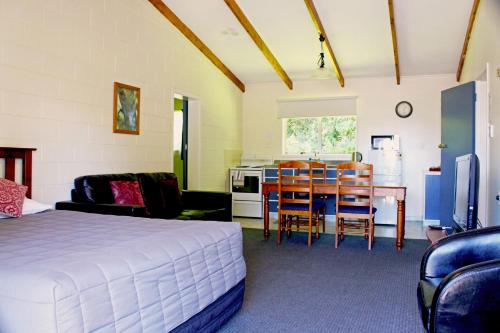 a bedroom with a bed and a table and a kitchen at Fairy Springs Motel in Rotorua