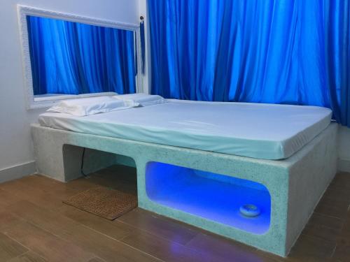 a bed in a room with blue curtains at Hotel MAI TUAN Chánh Môn A in Tây Ninh