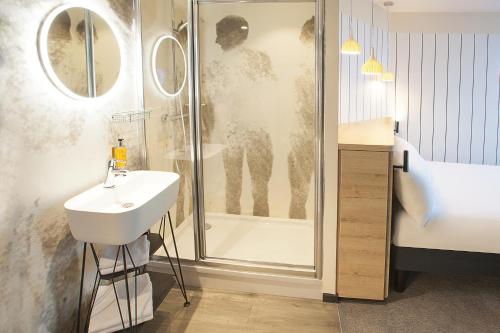 a bath room with a tub and a mirror at ibis Styles Paris 16 Boulogne in Paris