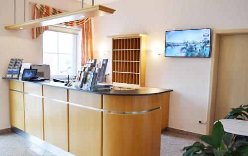 a waiting room with a counter and a tv on the wall at Hotel Nummerhof in Erding