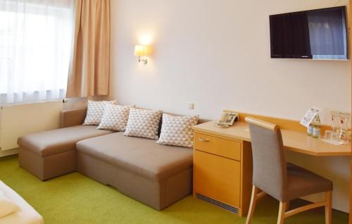 a hotel room with a couch and a desk at Hotel Nummerhof in Erding