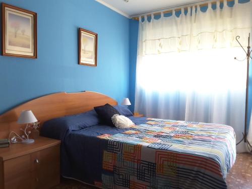 a bedroom with a bed with blue walls and a window at Benicanena in Gandía