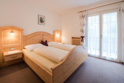 ein Schlafzimmer mit einem großen Bett und einem großen Fenster in der Unterkunft Garni Georgenhöhe in Schenna