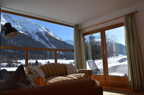 a living room with a view of a snow covered mountain at Residence Miragolf in Madulain