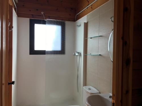 a bathroom with a toilet and a sink and a window at Camping Ribamar in Alcossebre