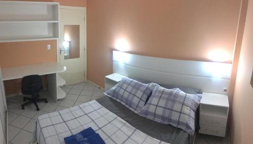 ein kleines Schlafzimmer mit einem Bett und einem Schreibtisch in der Unterkunft Apartamento Centro dos Ingleses in Florianópolis