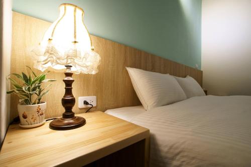 a lamp on a wooden table next to a bed at Free wind B&B in Taitung City