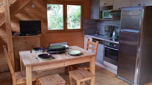 La cuisine est équipée d'une table en bois, d'une cuisinière et d'un réfrigérateur. dans l'établissement La cabane du pommier, à Orelle