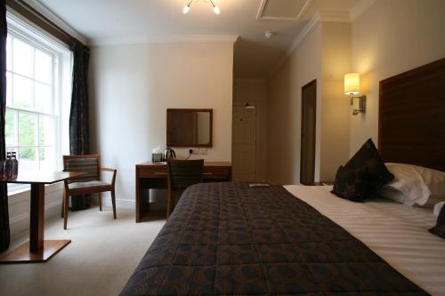 a hotel room with a bed and a table and a desk at Fishmore Hall Hotel and Boutique Spa in Ludlow