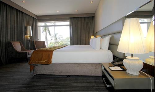 a hotel room with a bed and a table with a lamp at Coastlands Musgrave Hotel in Durban