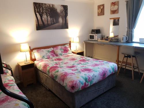 a bedroom with a bed, a desk and a painting on the wall at Chelford B&B in Marthall