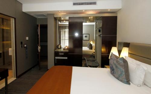 a hotel room with a large bed and a bathroom at Coastlands Musgrave Hotel in Durban