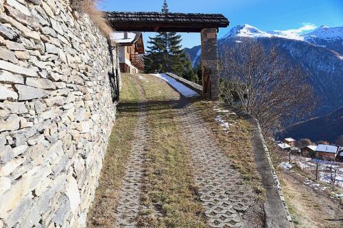 a stone wall with a bridge over a dirt road at Magnifique chalet pour 10 personnes à Vercorin in Vercorin