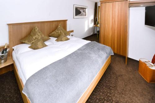 a bedroom with a large white bed with a wooden headboard at Hotel Alpina in Fiesch