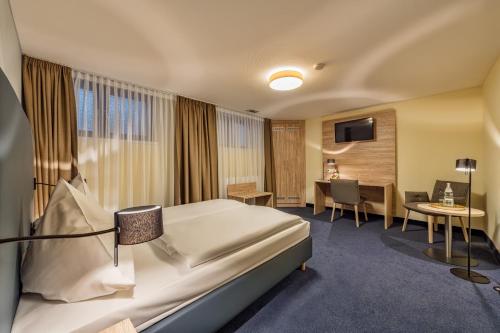 ケルンにあるホテル ウインザーのベッドとデスクが備わるホテルルームです。