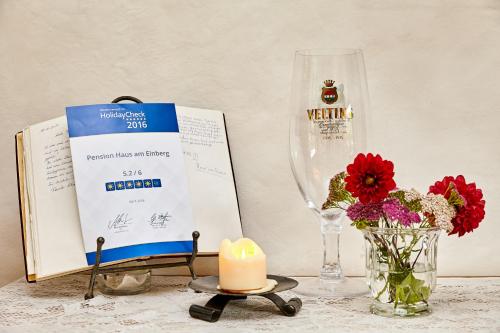 a candle and a vase with flowers and a wine glass at Pension Haus am Einberg in Meschede