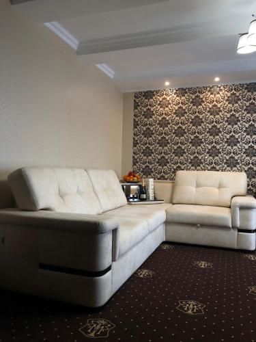 a living room with two white leather couches at Hotel Boutique TOVMED in Vinnytsya
