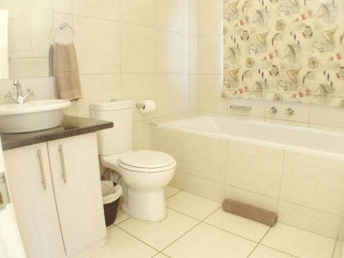 a bathroom with a toilet and a tub and a sink at Point Village Accommodation - Alista in Mossel Bay