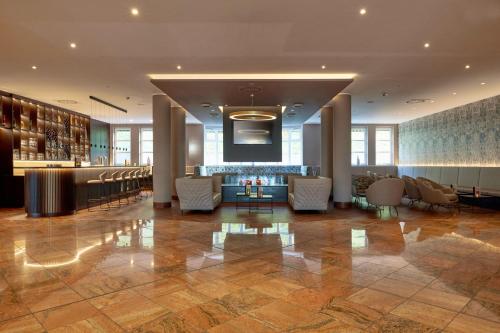a lobby of a hotel with chairs and a bar at H+ Hotel Limes Thermen Aalen in Aalen