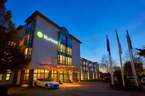 a building with a car parked in front of it at H+ Hotel Limes Thermen Aalen in Aalen