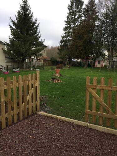 a wooden fence in a yard with a playground at La Vie est Belle in Abbeville