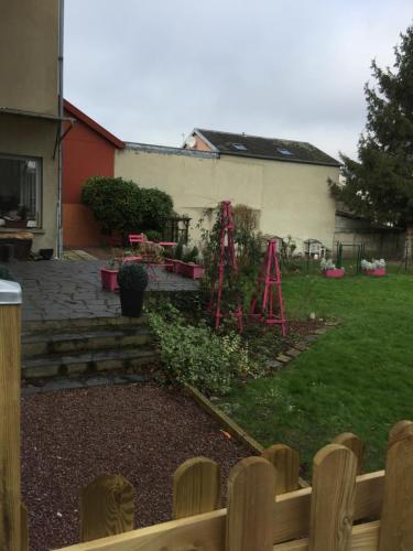 un patio trasero con un jardín con una valla y una casa en La Vie est Belle en Abbeville