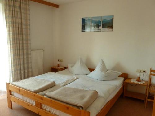 Schlafzimmer mit einem Bett mit weißer Bettwäsche und Kissen in der Unterkunft Ferienwohnung Maag in Lechbruck