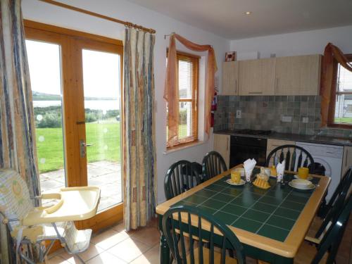 a kitchen with a table and chairs and a kitchen with a window at Achill Sound Holiday Village in Achill Sound