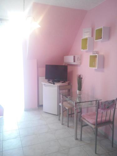 a dining room with a glass table and a television at Valloris Apartments in Hévíz