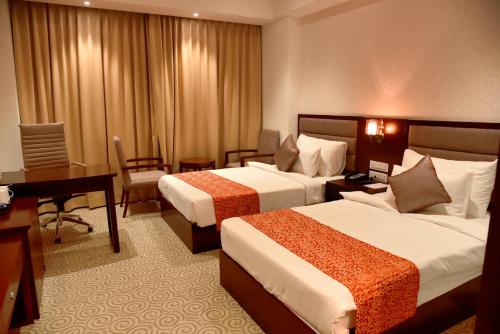 a hotel room with two beds and a desk at Pride Hotel & Convention Centre Indore in Indore