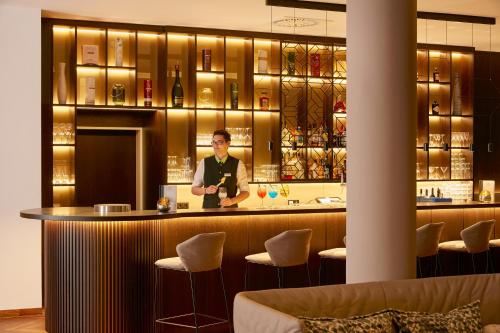 a man standing at a bar in a restaurant at H+ Hotel Limes Thermen Aalen in Aalen