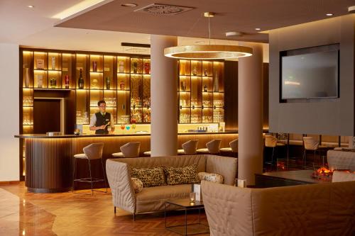 a hotel lobby with a bar and a man in the background at H+ Hotel Limes Thermen Aalen in Aalen