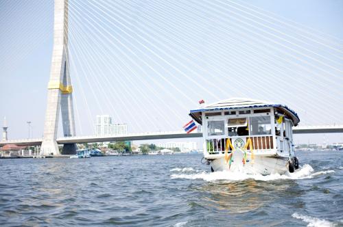 a boat in the water in front of a bridge at Praya Palazzo - SHA Plus in Bangkok