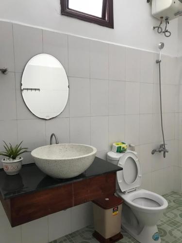 W łazience znajduje się umywalka, toaleta i lustro. w obiekcie Cheerful Hoi An Hostel w Hoi An