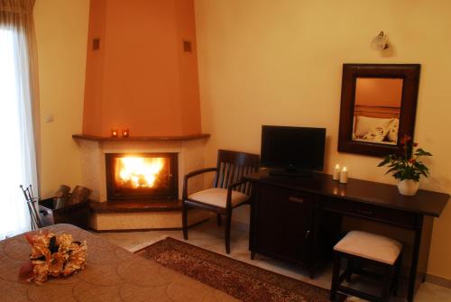a living room with a fireplace and a desk with a television at Asteras Hotel in Naousa Imathias