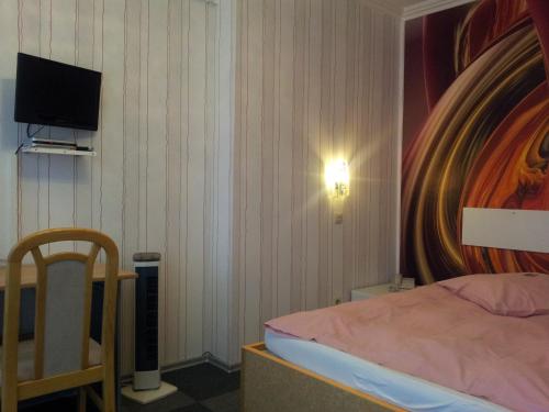 a bedroom with a bed and a tv on the wall at Am Hallenbad Hotel garni in Ratingen