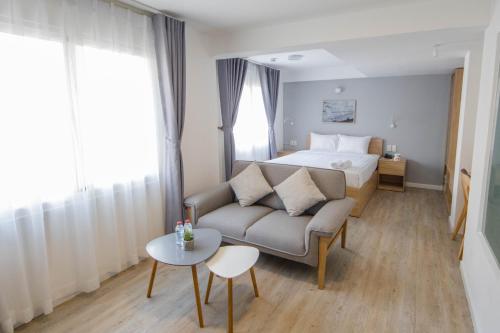 a bedroom with a bed and a couch and a table at Common Inn Thao Dien in Ho Chi Minh City