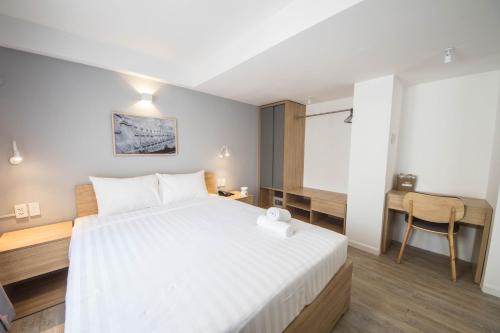 a bedroom with a large white bed and a desk at Common Inn Thao Dien in Ho Chi Minh City
