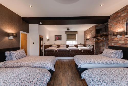 a bedroom with three beds and a brick wall at Tom Thumb Apartments in Liverpool