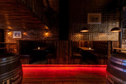 a bar with wooden tables and benches in a room with red lighting at Tom Thumb Apartments in Liverpool