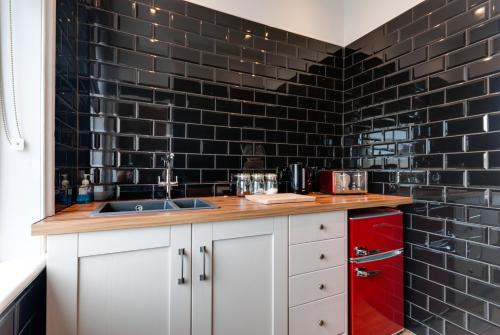 uma cozinha com um lavatório e uma parede de azulejos pretos em Tom Thumb Apartments em Liverpool