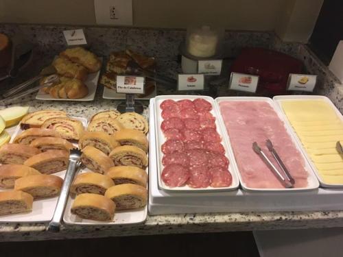 a buffet with different types of bread and meats and pastries at Barueri Premiêr Hotel in Barueri