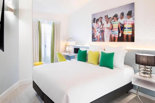 um quarto com uma cama branca com almofadas verdes e amarelas em Hôtel Dress Code em Paris