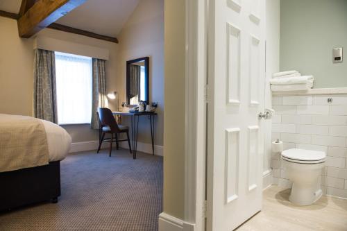 a bathroom with a bed and a toilet and a desk at The Kestrel by Innkeeper's Collection in Harrogate