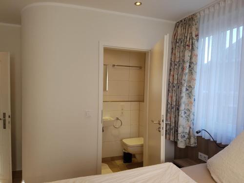 a bathroom with a bed and a toilet and a window at Hotel Pension Haus Pooth in Wesel