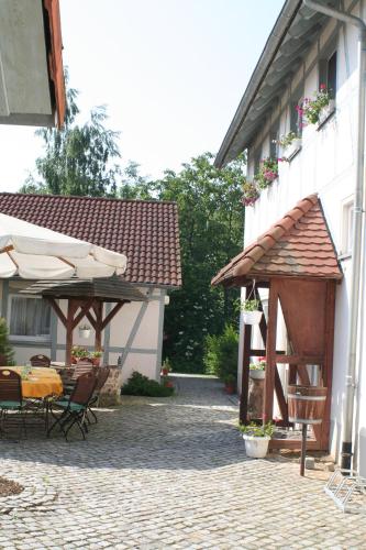 un patio con una mesa y sombrillas junto a un edificio en Landhotel "Zum Nicolaner" en Großweitzschen