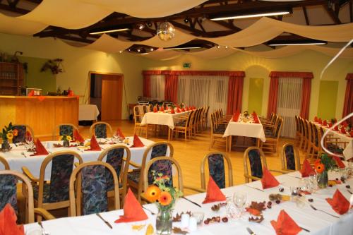 un salón de banquetes con mesas blancas y sillas con servilletas rojas en Landhotel "Zum Nicolaner" en Großweitzschen