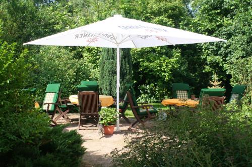 una mesa y sillas bajo una sombrilla blanca en Landhotel "Zum Nicolaner" en Großweitzschen